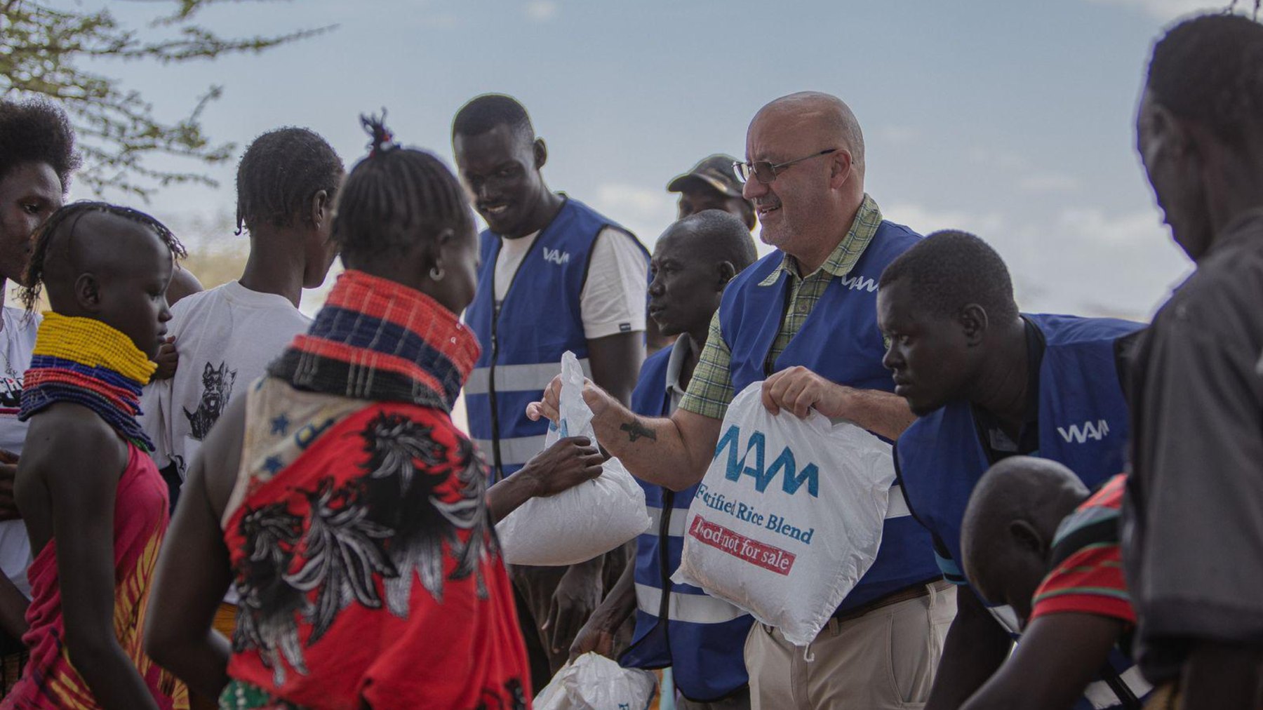 A WAM worker hands a sack of fortified rice to a woman at a distribution in Turkana, Kenya